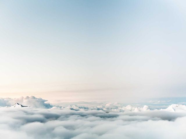 A summit above a floor of clouds at sunrise.
